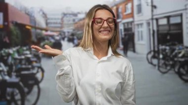 Meşgul şehir caddesinde elinde avucunda kırmızı gözlüklerle ve beyaz gömlekli bisikletle gülümseyen bir kadın..