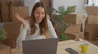 Taşınan kutular ve ev bitkileriyle dolu binada el ele sallayan kadın; mutluluk yeni bir başlangıç.