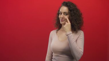 Kadın stüdyoda yanak yanağa ince bir gülümseme ve doğal duruş ile kamerayı doğrudan birbirine bağlıyor; özgüven.