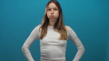 Yanakları şişen bir kadın, kalçasında elleri olan ve her iki işaret parmağıyla işaret eden bir kadın. Hem de beyaz, uzun kollu bir bluz giyerken..