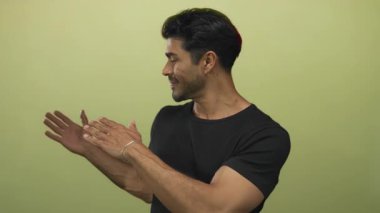 Kameraya bakarken soldaki yeşil stüdyoda gülümseyen ve kollarını sola çeviren İspanyol genç adam; iyimserlik iyimserliği pozitifliği sıcaklığı.