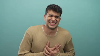 Genç İspanyol çocuk acı ve ıstırap çekerken adam mavi arka planda kalp debriyajı gösteriyor..