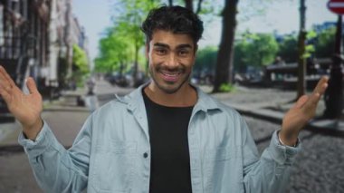 Genç İspanyol asıllı gülümseyen adam, yoğun şehir caddesinde büyük ölçümler için ellerini açar; güven açıklığı.