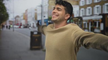 Erkek kolları açık havada şehrin erkek enerjisiyle İspanyol genç gülümseme sahnesinin arkasında gerilir..