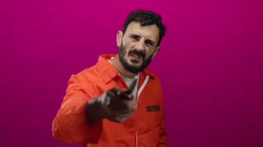 Turuncu hapishane tulumlu İspanyol adam pembe arka planda bıçak tutuyor, tehlike ve gerilim yaratıyor..