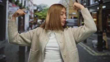 Bir kenar mahallede kaslarını esnetirken kendine güvenen bir kadın şehir ortamında güç ve pozitiflik sergiliyor..