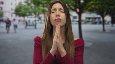 Elleri duaya bastırılmış genç İspanyol kadın hareketli şehir caddesinde; inanç umudu..