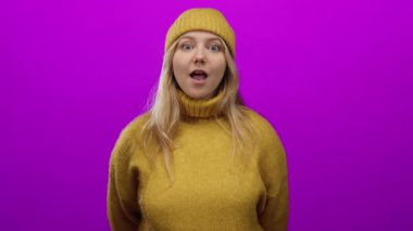 Sarı kazaklı ve bereli bir kadın canlı pembe bir arka plana karşı heyecanını ifade ediyor, neşeli ve neşeli bir ruh hali sergiliyor..