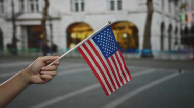 Beyaz adamın elinde Amerikan bayrağı var. Vatansever bir şehir manzarası yaratıyor. Arka planı bulanık..