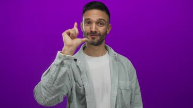 İspanyol asıllı genç adam, sıradan jestler yapıyor. Kameraya kaybeden işareti yapıyor. Canlı mor bir arkaplan, kendine güvenen bir ifadeyle, modern gündelik iletişim ipuçlarını somutlaştırıyor..