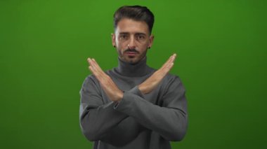 Stüdyoda çapraz kolları ve siyah küpeleri olan gri balıkçı yakalı genç İspanyol adam reddediyor..