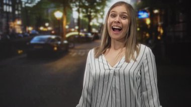 Genç sarışın kadın gülümser sonra gece lamba ışığı altında kaldırım taşı şehir caddesinde kaşlarını çatar; iç üzüntü geçiş.