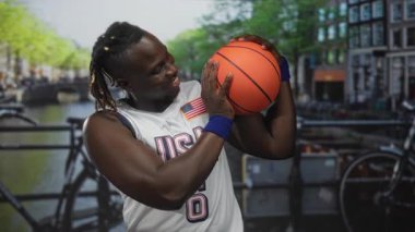 Elleri ve bilekliğiyle basketbol oynayan bir adam Amsterdam 'da sokak sokak sırıtarak ve kaslı kollarla gülümsüyor..