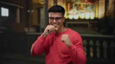 Gözlüklü, gülümseyen adam yumruk hareketi yapıyor.