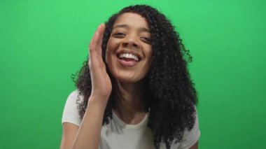 Afrika kökenli Amerikalı kadın avuç içini doldurur. Stüdyoda kıvırcık saçlar ve yeşil ekrana karşı parlak bir gülümseme ile. Mutluluk..
