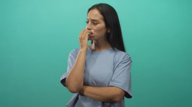 Turkuaz stüdyoda tırnaklarını yiyen genç İspanyol kadın. Endişe kaygısı, tereddüt..