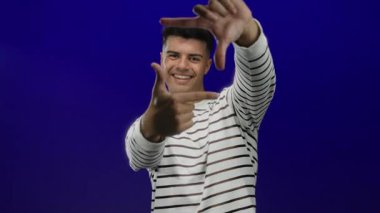 Gülümseyen adam elleriyle çerçeve hareketi yapıyor.