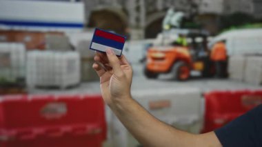 Bir inşaat sahasında Rus bayrağına benzeyen bir yama tutan adam çalışma ortamındaki kültürel kimlikleri vurguluyor..