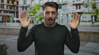 Genç İspanyol adam, şehrin işlek kaldırımları boyunca sürpriz bir hareketle iki elini kaldırır..
