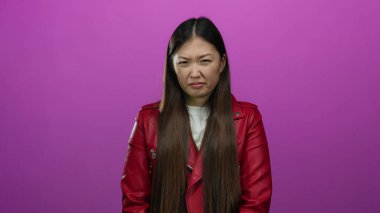 Kırmızı ceketli kadın, izole edilmiş pembe bir arka plana karşı tiksinti duyuyor..