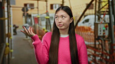 Şantiyede uzun saçlı pembe kazak giyen bir kadın hayal kırıklığına uğramış görünüyor. Şehir ortamında hayal kırıklığı ya da karmaşa olduğunu söylüyor..