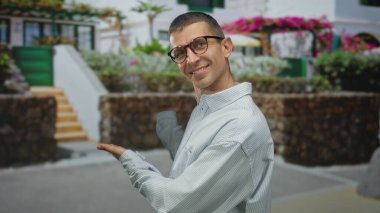 Doğanın ve manzaranın çerçevelediği kentsel alanda açık havada gülümseyen bir adam, güzel evi çiçeklerle ve taş çitlerle donatıyor..