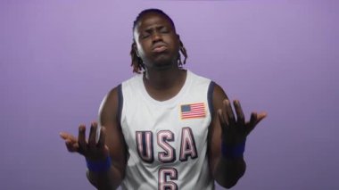 ABD basketbol formalı, mavi bileklikli bir adam mor stüdyoda baş ağrısı için el ele tutuşuyor..