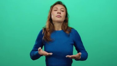 Tecrit edilmiş yeşil arka plana karşı çeşitli duyguları ifade eden, mavi süveter giyen, konuşma ya da tartışma öneren jestler gösteren bir kadın.