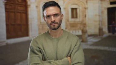 Üniversite kampüsünde kolları eski binaya dönük genç bir İspanyol adam. Düşünceli ve düşünceli bir süveter giyip derin düşüncelere dalmış..