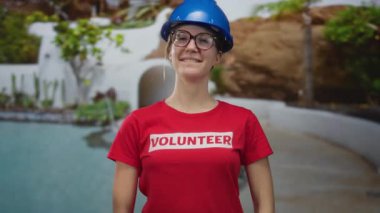 Kırmızı gönüllü gömlekli ve mavi şapkalı kadın, gözlüklü havuz başında el ele tutuşuyor; kamu hizmeti.