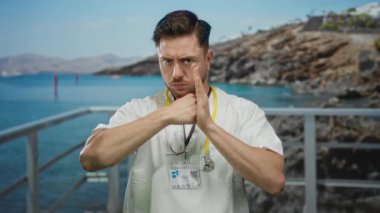 Steteskoplu genç, beyaz sakallı doktor sahilde güneşli bir günde deniz kenarında medikal profesyonelliği deniz kenarına karıştırarak savaş jesti yapıyor..