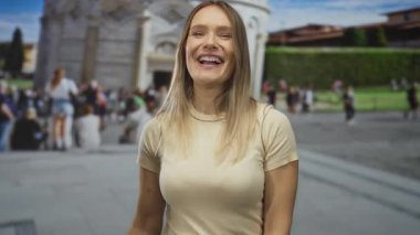 Güneşli bir günde, İtalya 'nın bir caddesinde kalabalıkken Pisa Kulesi' nin önünde gülümseyen bir kadın jest yapıyor..