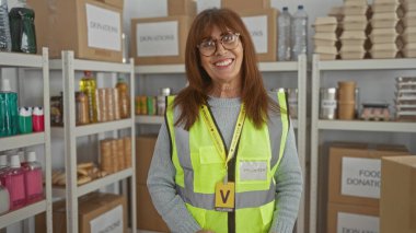 Bağış merkezinde çalışan üst düzey bir kadın. Toplum destek çabalarının sergilendiği kapalı bir tesiste etiketleme ve ambalajlama üzerine yoğunlaşmış eşyalar düzenliyor.