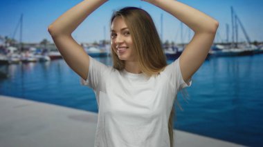 İskelede kollarını kaldırıp gülümseyen bir kadın, güneşli bir günde suyun tadını çıkarıyor, mutluluğu ve gençlik enerjisini yakalıyor..