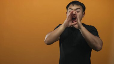 Stüdyoda genç Çinli bir adam kulağını öne eğip dikkatlice dinlemek için elini kaldırıyor..