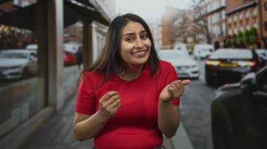 Göğüs göğüse küçük kırmızı bir kalp tutan ve kalabalık bir şehir caddesinde geçen arabalar ve yayalar ile bir öpücük üfleyen kadın, umut dolu bir aşk..
