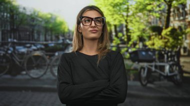 Amsterdam Kanal Bölgesi 'nde kolları çapraz ve dudakları büzüşmüş, büyük gözlüklü bir kadın..