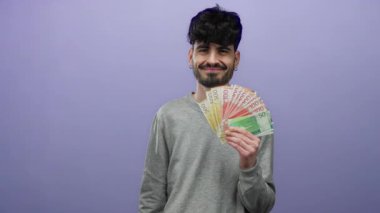 Elinde mor bir zemin üzerinde Norveç banknotları tutan genç bir adam, kendine güvenen bir ifadeyle sıradan bir ortamda krone para gösteriyor.