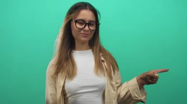 Gözlüklü kadın elini gösterip yeşil bir stüdyoda beyaz bluz ve bej gömlek giyerken beni arayıp jest yaptırıyor..