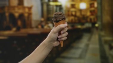 Kilise ortamında el ele tutuşan çikolatalı dondurma külahı, erkek varlığı ve mimari geçmişi ile kutsal ve boş zamanların yan yana gelişini sembolize ediyor..