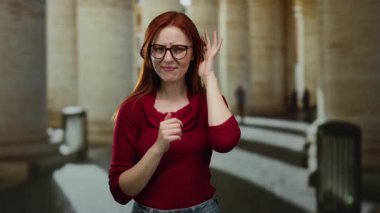 Sütunların yanında duran gözlüklü kadın.