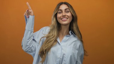 Turuncu stüdyo ortamında sol üst köşeyi gösteren sarışın kadın parmağı..