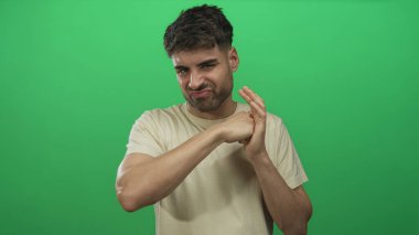 Genç İspanyol adam, basit yeşil stüdyo duvarına sıkılmış yumruğuyla yumruk atıyor. Kararlılık..