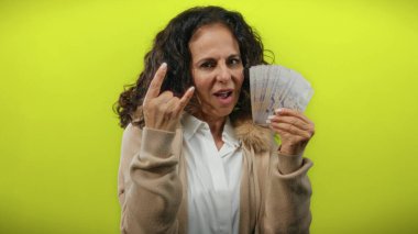 Orta yaşlı bir kadın taştan bir jest yapıyor ve sarı bir arka plana karşı Singapur doları tutuyor..