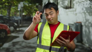 Şehir caddesinde elinde bir pano tutan, şehir ortamında kendinden emin ve profesyonel görünen, açık hava iş ortamı sunan, yüksek görüşlü bir adam..