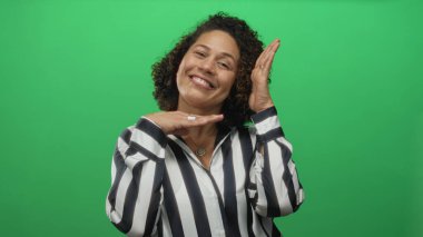 Yeşil stüdyoda elleri olan orta yaşlı, gülümseyen bir kadın..