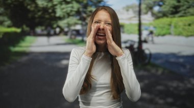 Park halindeki bisikletle kıt kanaat geçinen, gülümseyen ve öne doğru eğilen kadın sanki bağırıyormuş gibi; neşeli bir duyuru.