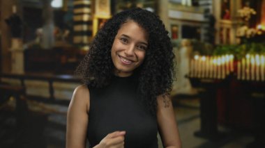 Gülümseyen genç İspanyol kadın kilise binasında elleri ile işaret ediyor; barışçıl davet halk inancı..