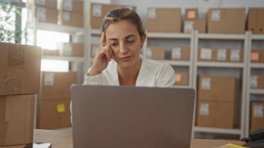 Bir binada parsel ve dizüstü bilgisayara bakarken tapınağa dokunan kadın; envanter planlama ile ilgili endişe.