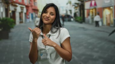 Gülümseyen uzun saçlı genç Latin kadın sokaklarda heyecan verici bir şekilde dolaşıyor. Etrafı şehirli dükkanlar ve renkli binalarla çevrili. Hispanik canlılık ve açık hava etkileşimleriyle dolu..